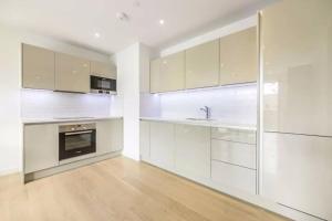 uma cozinha com armários brancos e um lavatório em Stunning Zone 1 Luxury Brand New 2 Bed Apartment em Londres