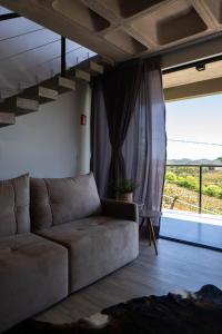 een woonkamer met een bank en een groot raam bij Döra Pousada e Enoturismo - Vale Dos Vinhedos in Bento Gonçalves