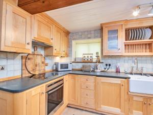 una cocina con armarios de madera y fregadero en North Lodge, en Bakewell