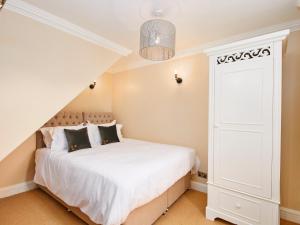 1 dormitorio con cama blanca y armario en North Lodge, en Bakewell