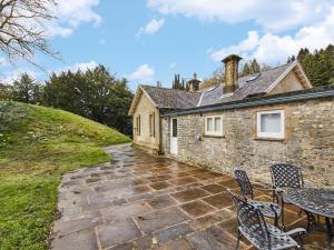 a stone house with a patio and a table and chairs at North Lodge in Bakewell