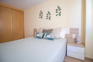 1 dormitorio con 1 cama blanca grande con almohadas azules en Aqua - Apartamento a 250m playa, en La Pineda