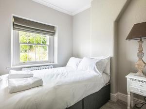 Schlafzimmer mit einem Bett mit weißer Bettwäsche und einem Fenster in der Unterkunft The Belle in Bakewell