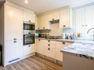 a kitchen with white cabinets and marble counter tops at The Aubrey in Bakewell