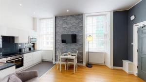Trueman Street Apartments في ليفربول: مطبخ وغرفة معيشة مع طاولة وتلفزيون