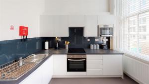 Trueman Street Apartments في ليفربول: مطبخ مع دواليب بيضاء ومغسلة