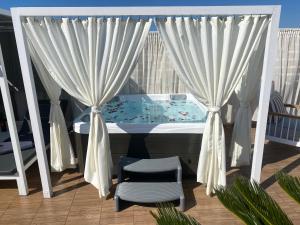a balcony with a tub with curtains and a chair at Residenza Rithymna Centro with a private roof terrace and hot tub in Rethymno