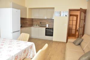 a kitchen with a table and a white refrigerator at Trimaya apartment - comfort in the top city center in Varna City