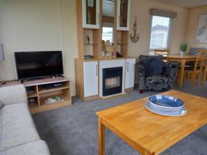 sala de estar con sofá, mesa y TV en Sunny Hunny Manor Park Caravan, en Hunstanton