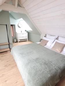 een slaapkamer met een groot bed op zolder bij Le jardin Médicis avec jacuzzi et sauna privatifs in Trédion