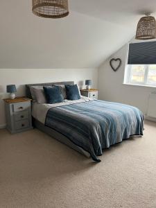 a bedroom with a bed with blue pillows and a window at Bescot House Bramble Hill Bude 4 bed det house in Bude