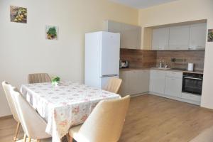 a kitchen with a table with chairs and a white refrigerator at Trimaya apartment - comfort in the top city center in Varna City