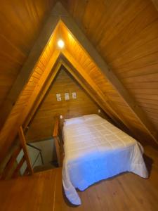 a bed in the attic of a wooden house at Chalé Verdant in Canoinhas