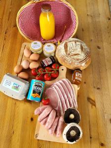a table with a ham and other food on a cutting board at Lanterns Shepherds Huts & Glamping in Happisburgh