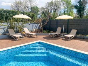 a swimming pool with two chairs and two umbrellas at Sunny Adriatic in Poreč