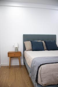 a bedroom with a bed with blue pillows and a table at Apartamentos Fleming in Albacete