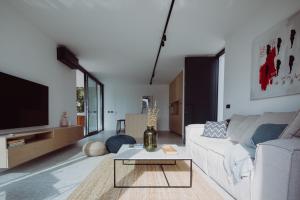 a living room with a white couch and a tv at D-Tree HOUSE private heated pool in Potocnica