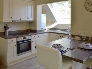 a kitchen with white cabinets and a table with chairs at Little Hoot in Baslow