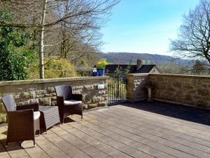 a patio with two chairs and a stone wall at Little Hoot in Baslow