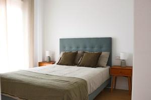 a bed with a blue headboard in a bedroom at Apartamentos Fleming in Albacete