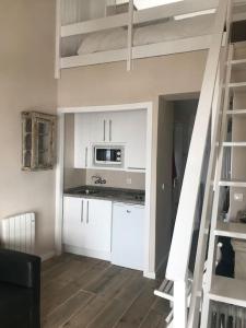uma cozinha com armários brancos e uma escada num quarto em Duplex con vistas fantásticas em Monachil