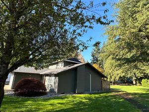 a green house with a tree in the yard at Cozy and Quiet Family Home in Park Setting Near PDX in Vancouver