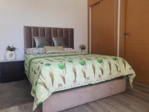 a bedroom with a bed with a green and white comforter at HEAVEN BEACH in Sidi Rahal