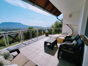a balcony with chairs and a view of the mountains at Délibáb Apartman in Szigliget