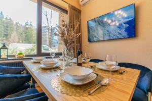 a wooden table with plates and wine glasses on it at Piaseckiego Residence SPA in Zakopane
