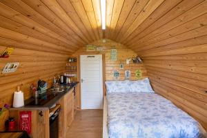 a bedroom in a log cabin with a bed in it at Lanterns Shepherds Huts & Glamping in Happisburgh