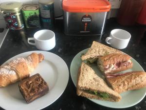 倫敦的住宿－Norfolk House，一张桌子,上面放着两盘三明治和羊角面包