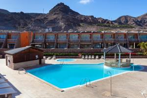 uma piscina em frente a um hotel com montanhas ao fundo em Luxuriösen Apartment am Meer Golfplatz, Strand em Playa del Cura