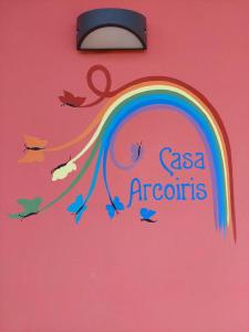 un cartel con un arco iris y pájaros en una pared rosa en Casa Arcoiris by Garda Facilities, en Manerba del Garda