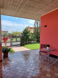 un patio con una mesa y una pared roja en Casa Arcoiris by Garda Facilities, en Manerba del Garda