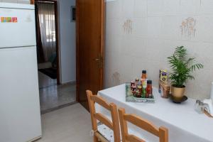 Il comprend une cuisine équipée d'une table blanche et d'un réfrigérateur blanc. dans l'établissement Palaikastro Holiday Apartment, à Siteía
