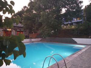 a blue swimming pool with trees in the background at TSIGOURA VERDE RESORT in Mikrós Prínos