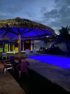 a pool with a table and chairs and an umbrella at POUSADA ESTRELA DA MANHÃ in Barreirinhas