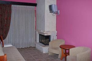 a living room with a fireplace and a tv at TSIGOURA VERDE RESORT in Mikros Prinos