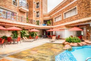 un patio del hotel con piscina, mesas y sombrillas en Hotel Windsor Barranquilla, en Barranquilla