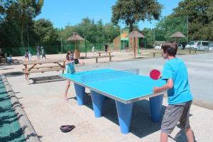 Chłopiec i dziewczynka grający w ping-ponga na stole do ping-ponga w obiekcie Camping Bretignolles-sur-Mer w mieście Brétignolles-sur-Mer