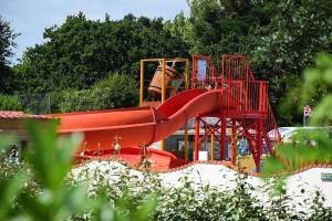 plac zabaw z czerwoną zjeżdżalnią w parku w obiekcie Camping Bretignolles-sur-Mer w mieście Brétignolles-sur-Mer +6 zdjęć