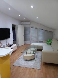 a living room with a white couch and a tv at Vila Nastovski in Veles