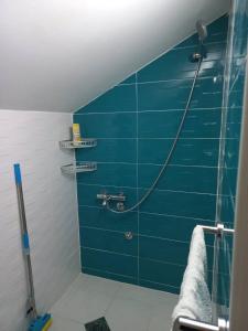 La salle de bains est pourvue d'un mur en carrelage bleu et d'une douche. dans l'établissement Vila Nastovski, à Veles