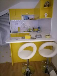 a kitchen with a yellow counter and two white stools at Vila Nastovski in Veles