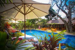 a person sitting under an umbrella next to a swimming pool at La Mer Resort, Phú Quốc in Phú Quốc