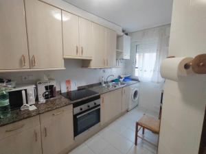 a kitchen with white cabinets and a sink and a dishwasher at Piso en Ajo con piscina comunitaria in Ajo