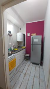 a kitchen with a white refrigerator and a purple wall at Guest House Santiago in Santiago del Estero