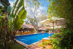 einen Pool in einem Resort mit Leuten, die um ihn herum sitzen in der Unterkunft La Mer Resort, Phú Quốc in Phu Quoc