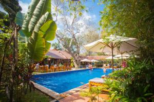 uma piscina num resort com pessoas sentadas à sua volta em La Mer Resort, Phú Quốc em Phu Quoc