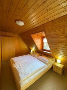 a bed in a room with a wooden ceiling at Chalupa U rybníčku in Krásná Lípa